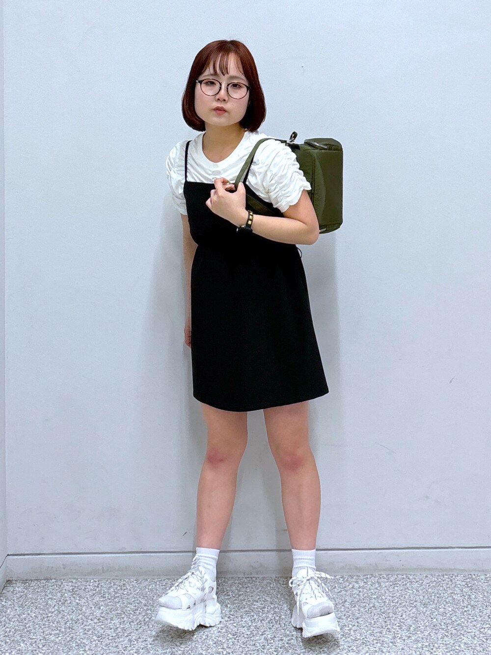 ブラック系のワンピース、グリーン系のショルダーバッグ、ホワイト系のサンダルを着用したレディースの春コーディネートの2枚目の写真
