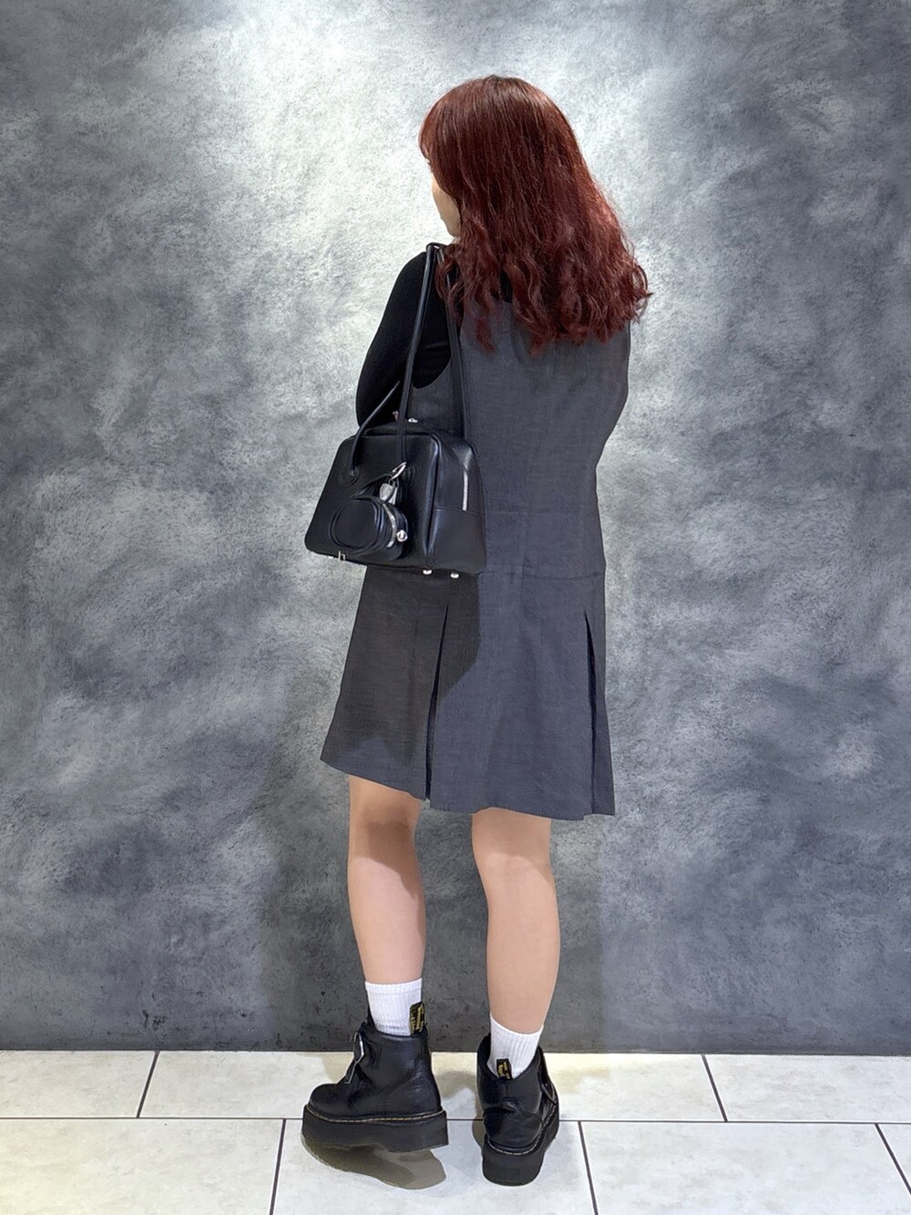 ブラック系のTシャツ/カットソー、ブラック系のブーツ、グレー系のジャンパースカートを着用したレディースの秋コーディネートの8枚目の写真