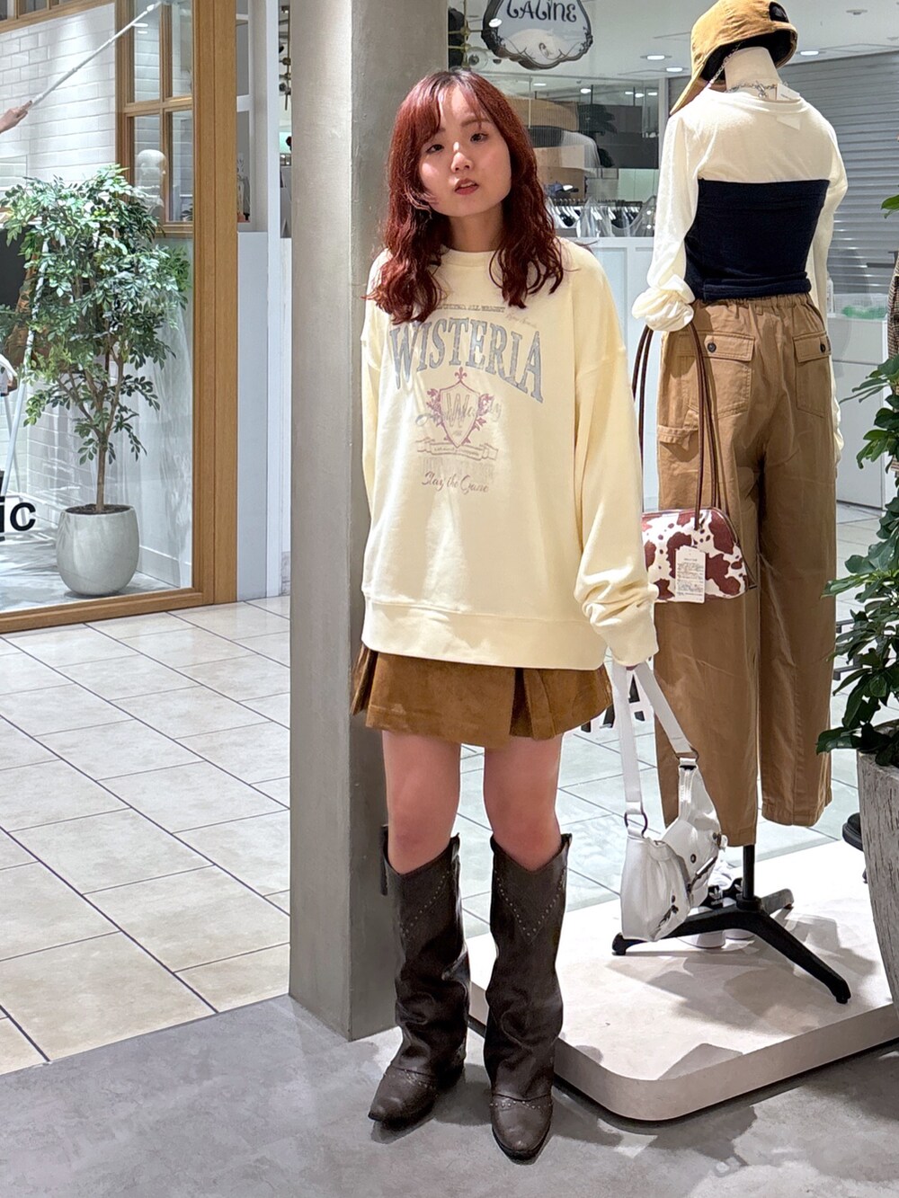 イエロー系のスウェット、ベージュ系のジャンパースカート、ホワイト系のショルダーバッグを着用したレディースの秋コーディネートの3枚目の写真