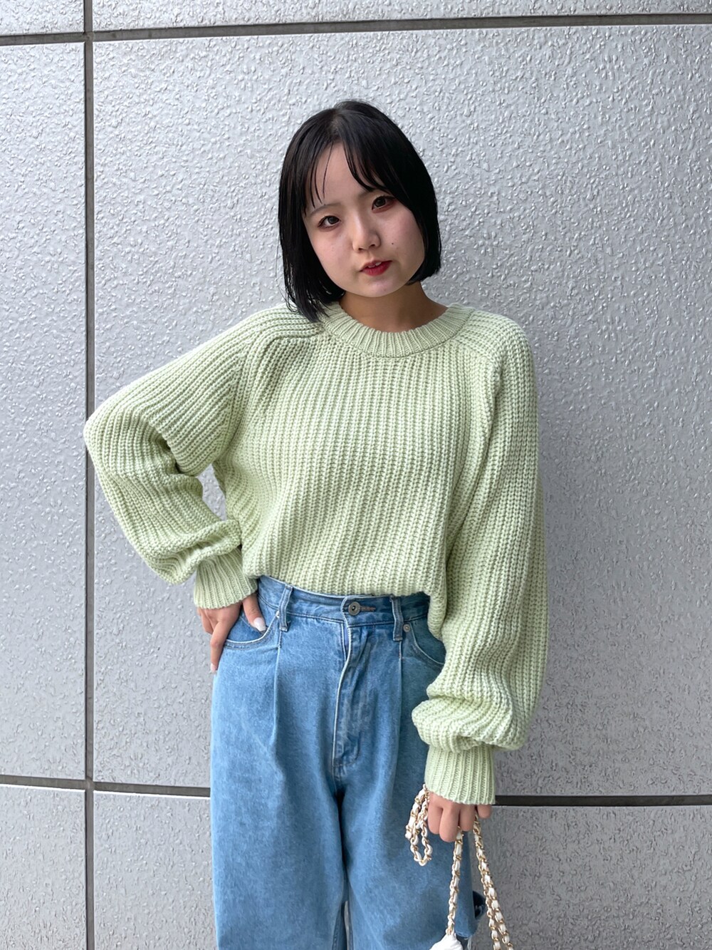 ホワイト系のトートバッグ、ブラック系のブーツ、ブルー系のデニムパンツを着用したレディースの秋コーディネートの4枚目の写真