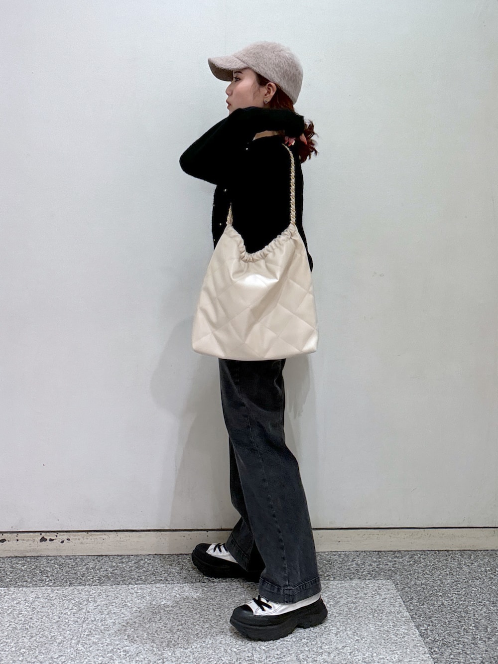 ブラック系のニット/セーター、ブラック系のデニムパンツ、ホワイト系のスニーカーを着用したレディースの冬コーディネートの4枚目の写真