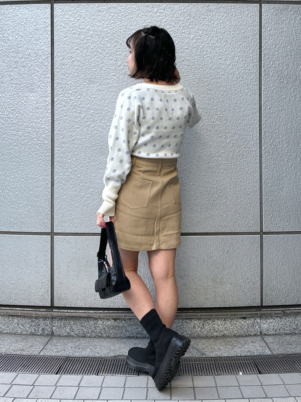 ブラック系のショルダーバッグ、ベージュ系のスカート、ホワイト系のニット/セーターを着用したレディースの冬コーディネートの3枚目の写真