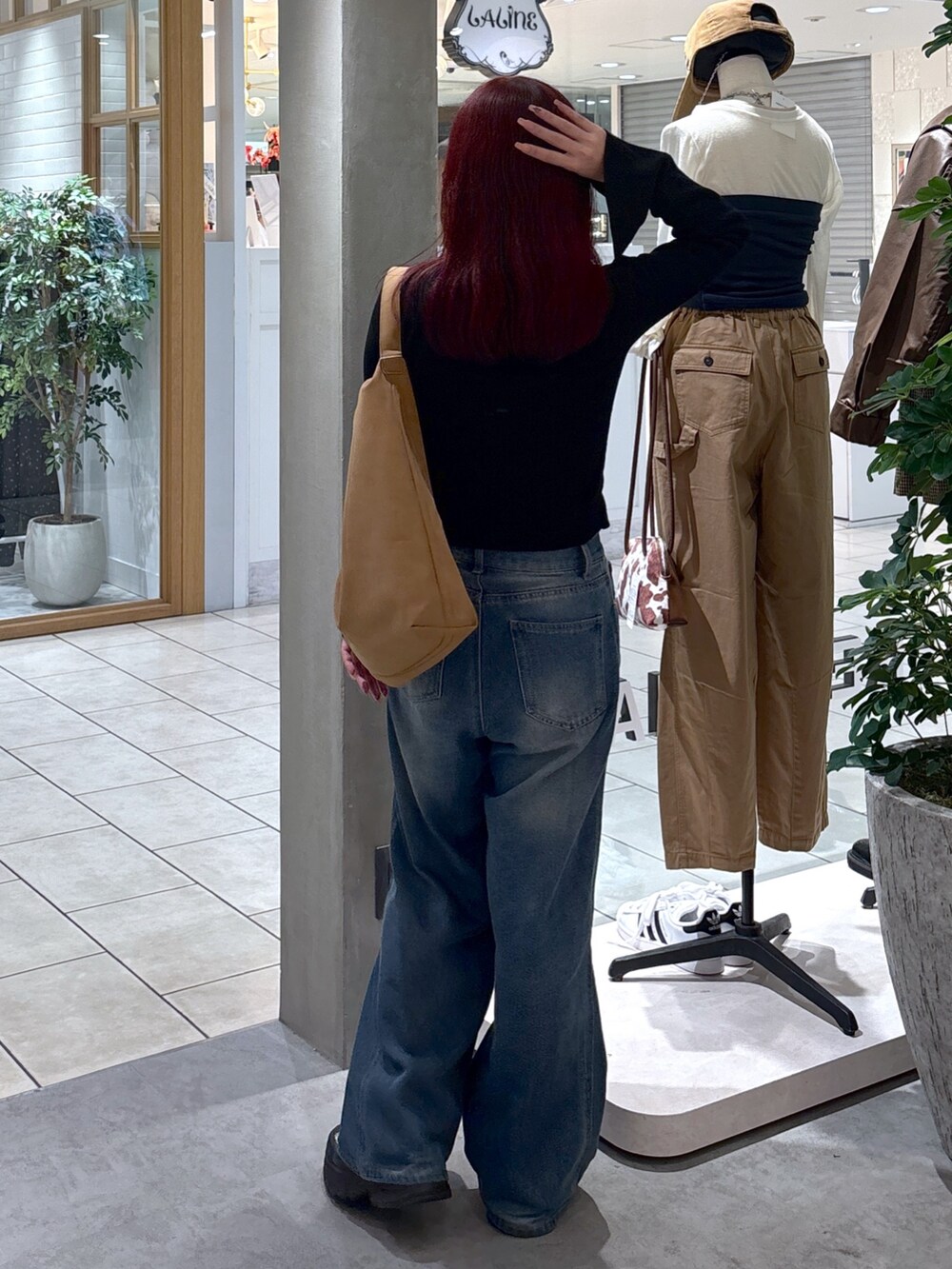 ブラック系のニット/セーター、ホワイト系のキャミソール、ブルー系のデニムパンツを着用したレディースの秋コーディネートの10枚目の写真