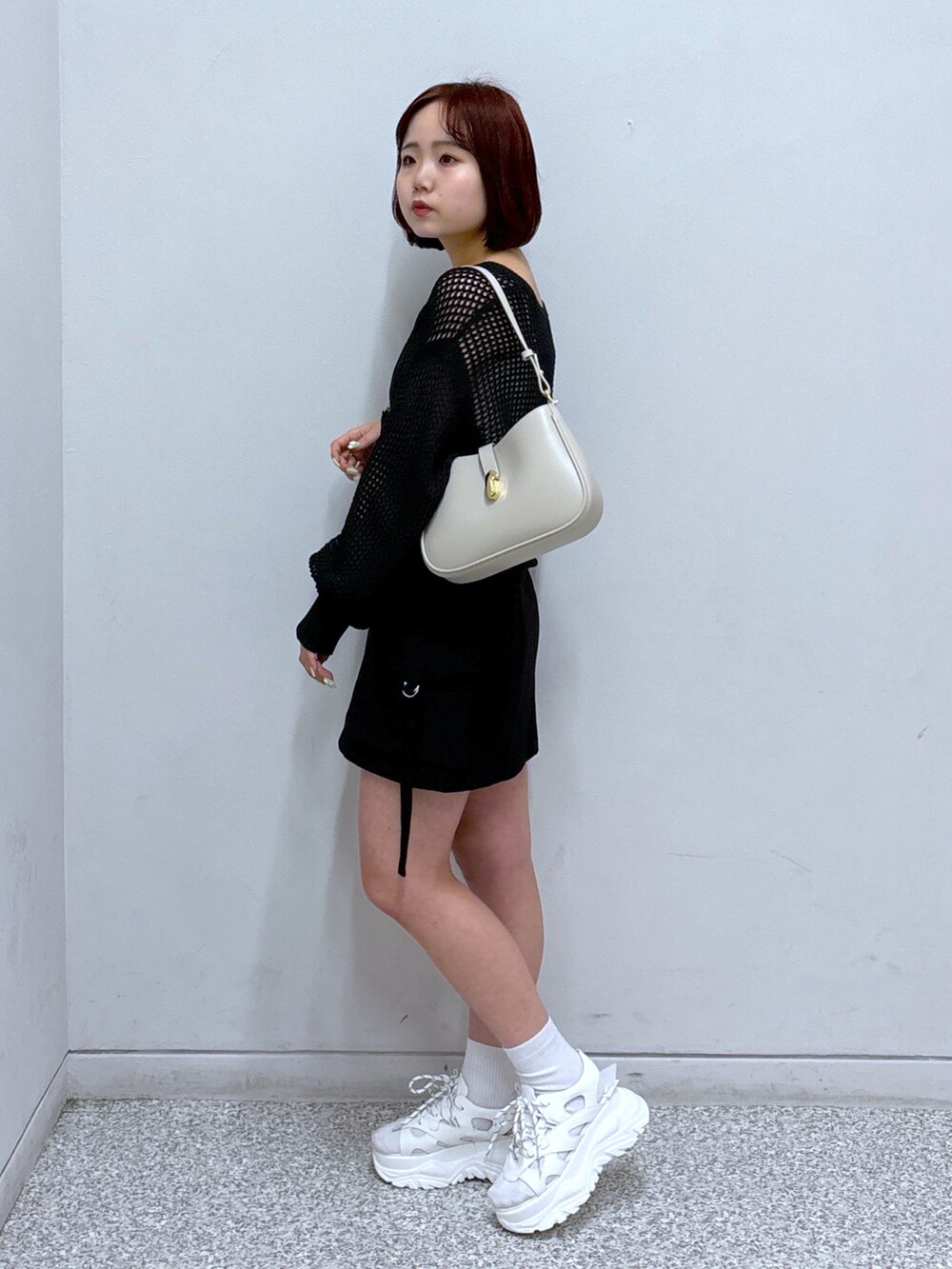 ホワイト系のサンダル、ブラック系のカーディガン/ボレロ、ブラック系のスカートを着用したレディースの春コーディネートの2枚目の写真