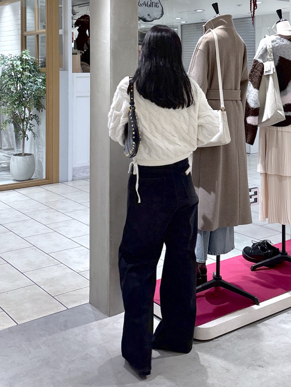 ホワイト系のニット/セーター、ブラック系のデニムパンツ、ブラック系のブーツを着用したレディースの冬コーディネートの7枚目の写真