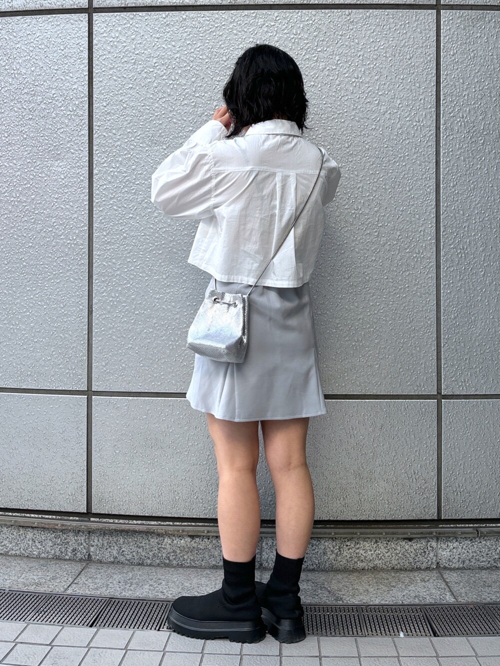 グレー系のスカート、ホワイト系のシャツ/ブラウス、シルバー系のハンドバッグを着用したレディースの冬コーディネートの3枚目の写真