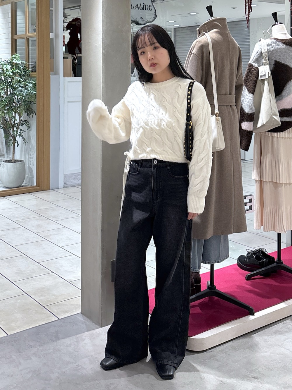 ホワイト系のニット/セーター、ブラック系のデニムパンツ、ブラック系のブーツを着用したレディースの冬コーディネートの2枚目の写真