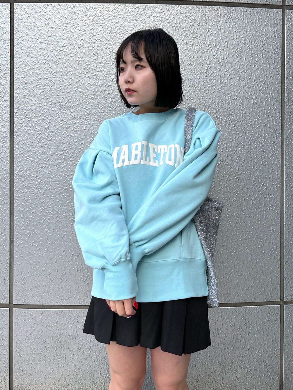 ブラック系のスカート、ブルー系のスウェット、シルバー系のトートバッグを着用したレディースの冬コーディネートの4枚目の写真