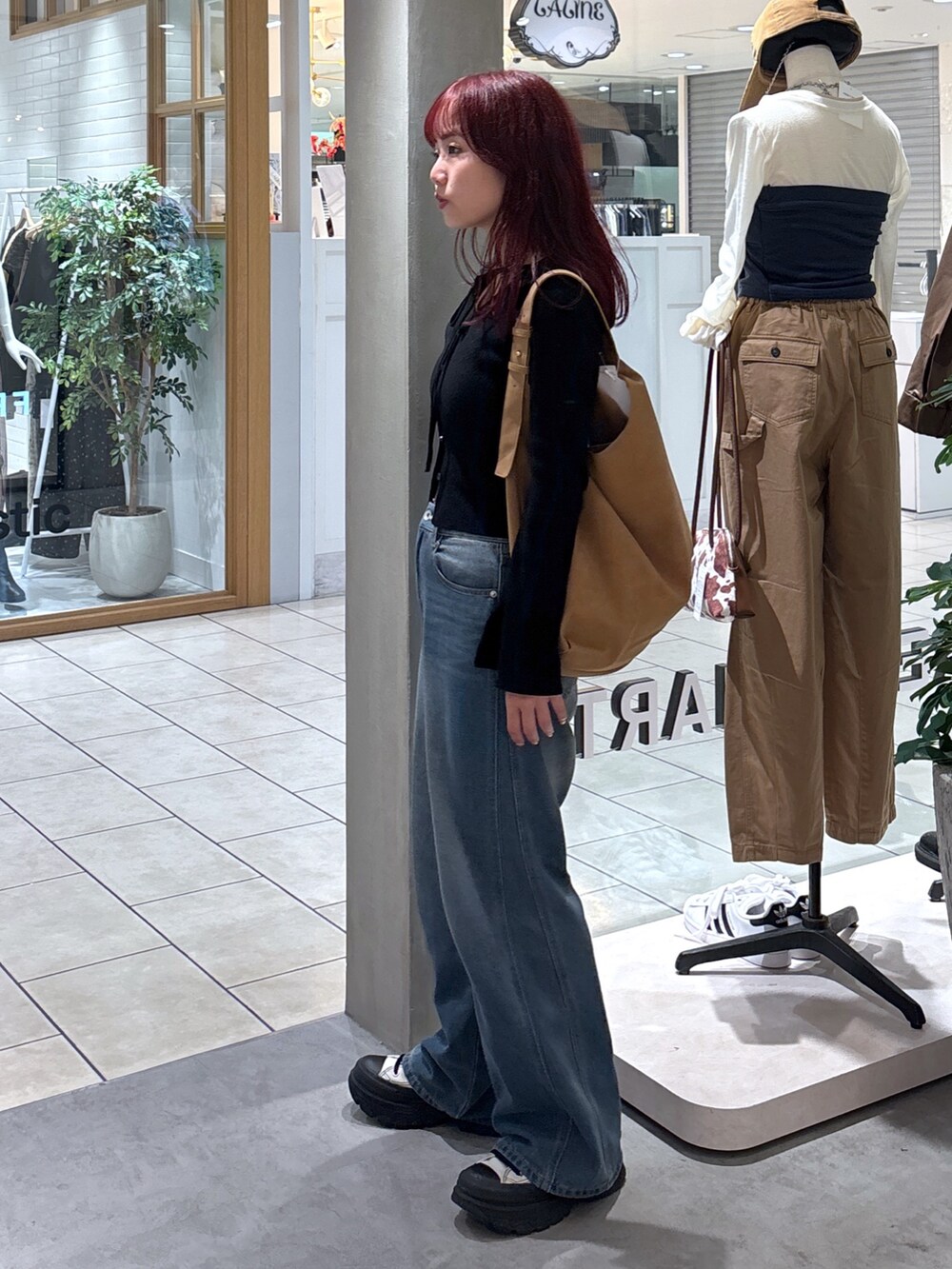 ブラック系のニット/セーター、ホワイト系のキャミソール、ブルー系のデニムパンツを着用したレディースの秋コーディネートの7枚目の写真