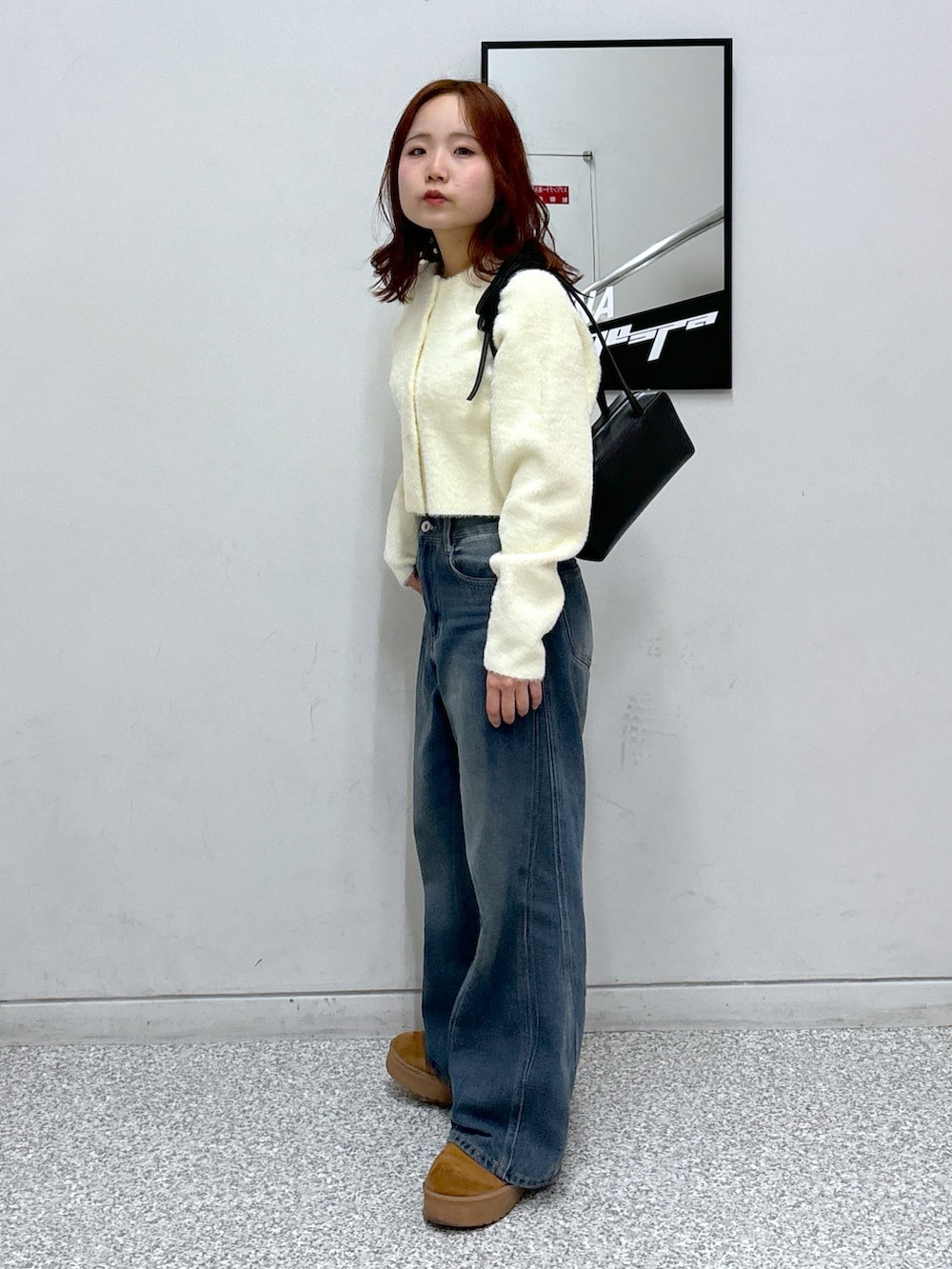 ホワイト系のカーディガン/ボレロ、ブラック系のショルダーバッグ、ブルー系のデニムパンツを着用したレディースの冬コーディネートの3枚目の写真