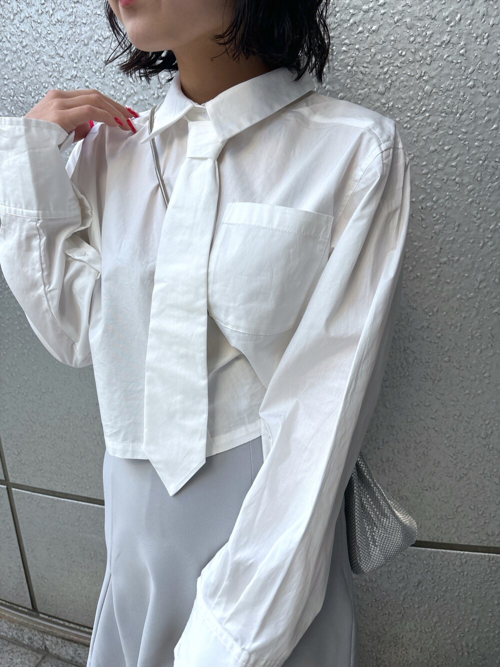 グレー系のスカート、ホワイト系のシャツ/ブラウス、シルバー系のハンドバッグを着用したレディースの冬コーディネートの4枚目の写真