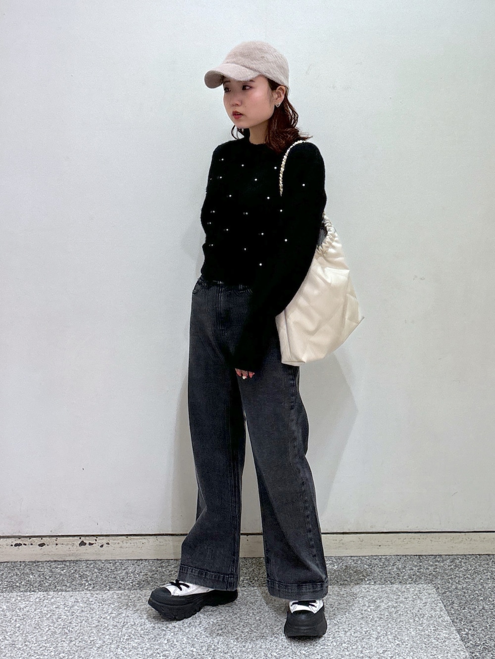 ブラック系のニット/セーター、ブラック系のデニムパンツ、ホワイト系のスニーカーを着用したレディースの冬コーディネートの3枚目の写真