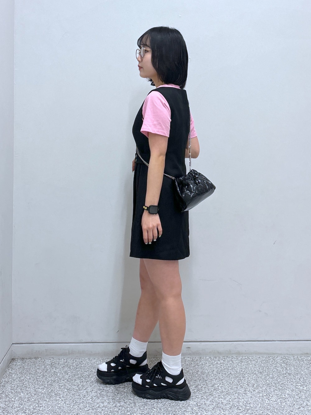 ブラック系のジャンパースカート、ブラック系のサンダル、ピンク系のTシャツ/カットソーを着用したレディースの春コーディネートの3枚目の写真