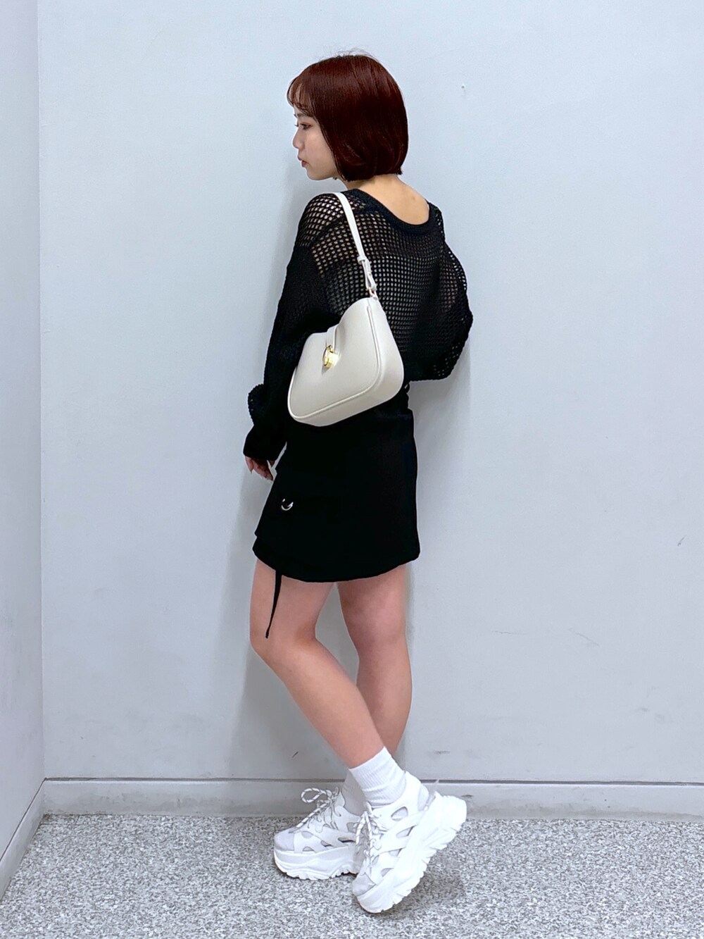 ホワイト系のサンダル、ブラック系のカーディガン/ボレロ、ブラック系のスカートを着用したレディースの春コーディネートの3枚目の写真