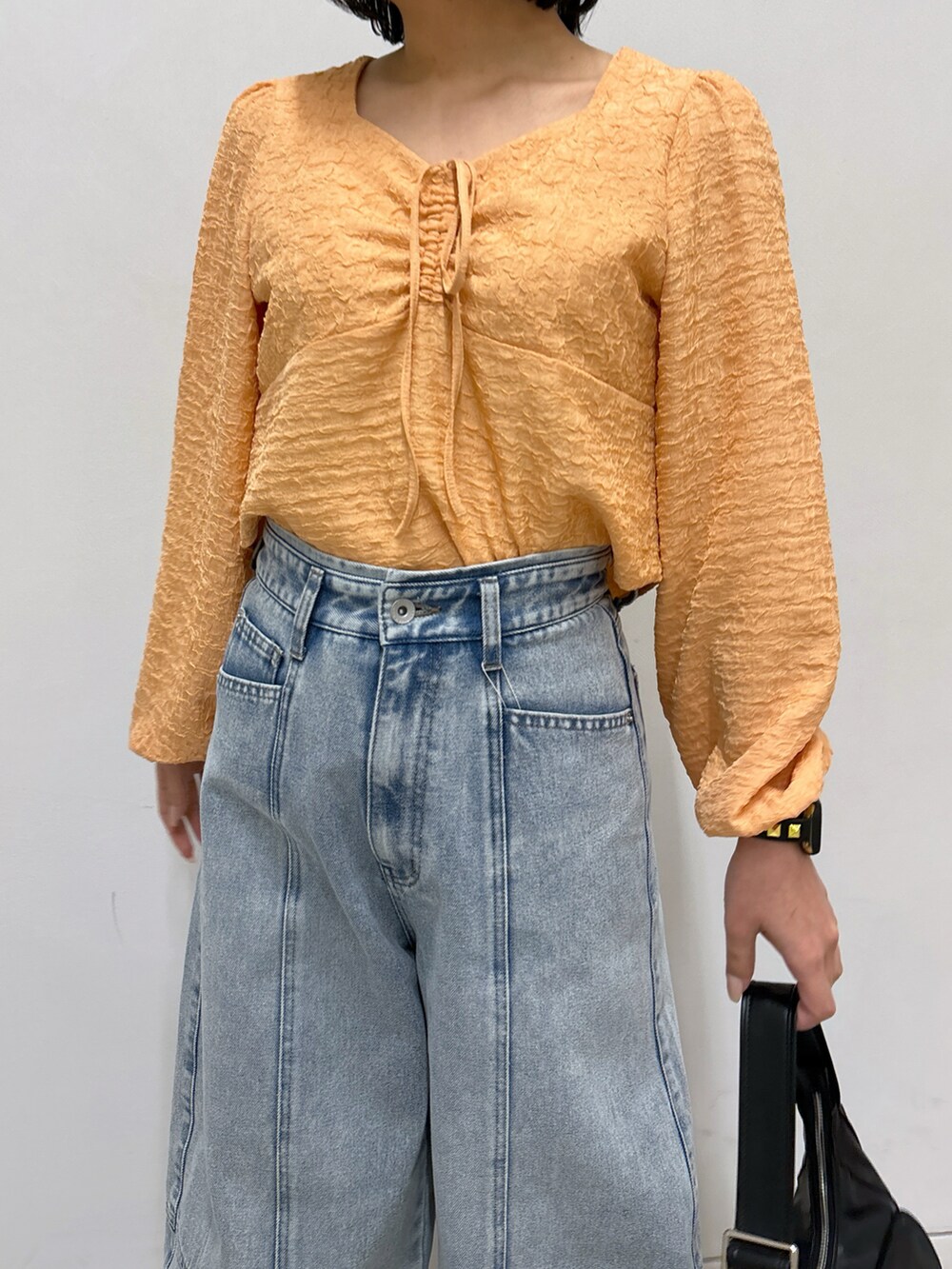 ブルー系のデニムパンツ、オレンジ系のシャツ/ブラウス、ベージュ系のパンプスを着用したレディースの春コーディネートの5枚目の写真