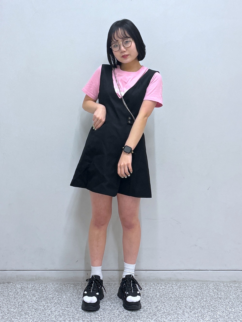 ブラック系のジャンパースカート、ブラック系のサンダル、ピンク系のTシャツ/カットソーを着用したレディースの春コーディネートの2枚目の写真