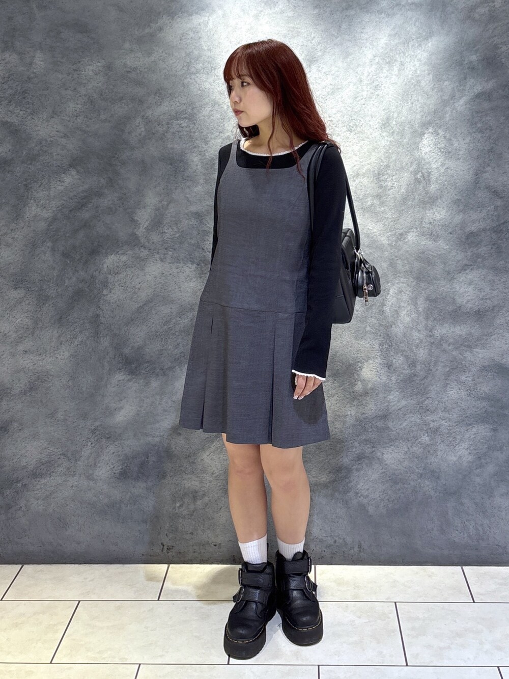 ブラック系のTシャツ/カットソー、ブラック系のブーツ、グレー系のジャンパースカートを着用したレディースの秋コーディネートの4枚目の写真