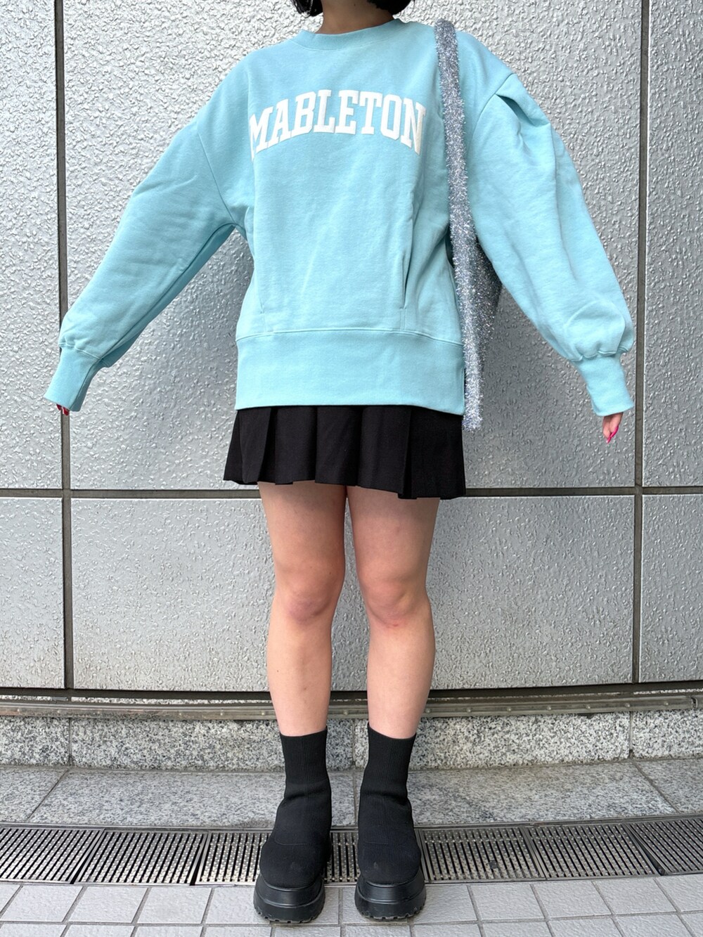 ブラック系のスカート、ブルー系のスウェット、シルバー系のトートバッグを着用したレディースの冬コーディネートの5枚目の写真