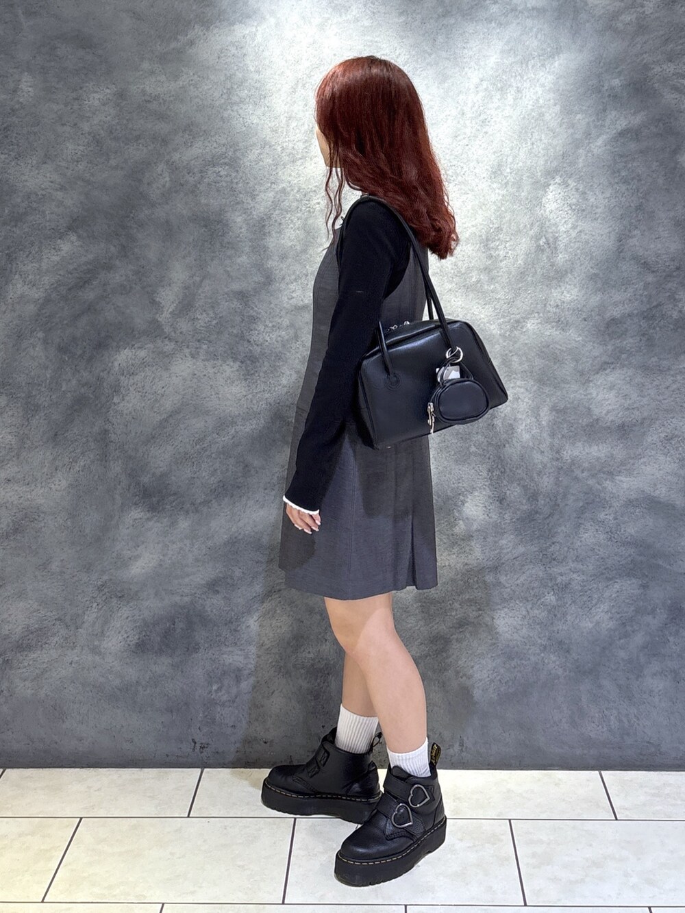 ブラック系のTシャツ/カットソー、ブラック系のブーツ、グレー系のジャンパースカートを着用したレディースの秋コーディネートの6枚目の写真