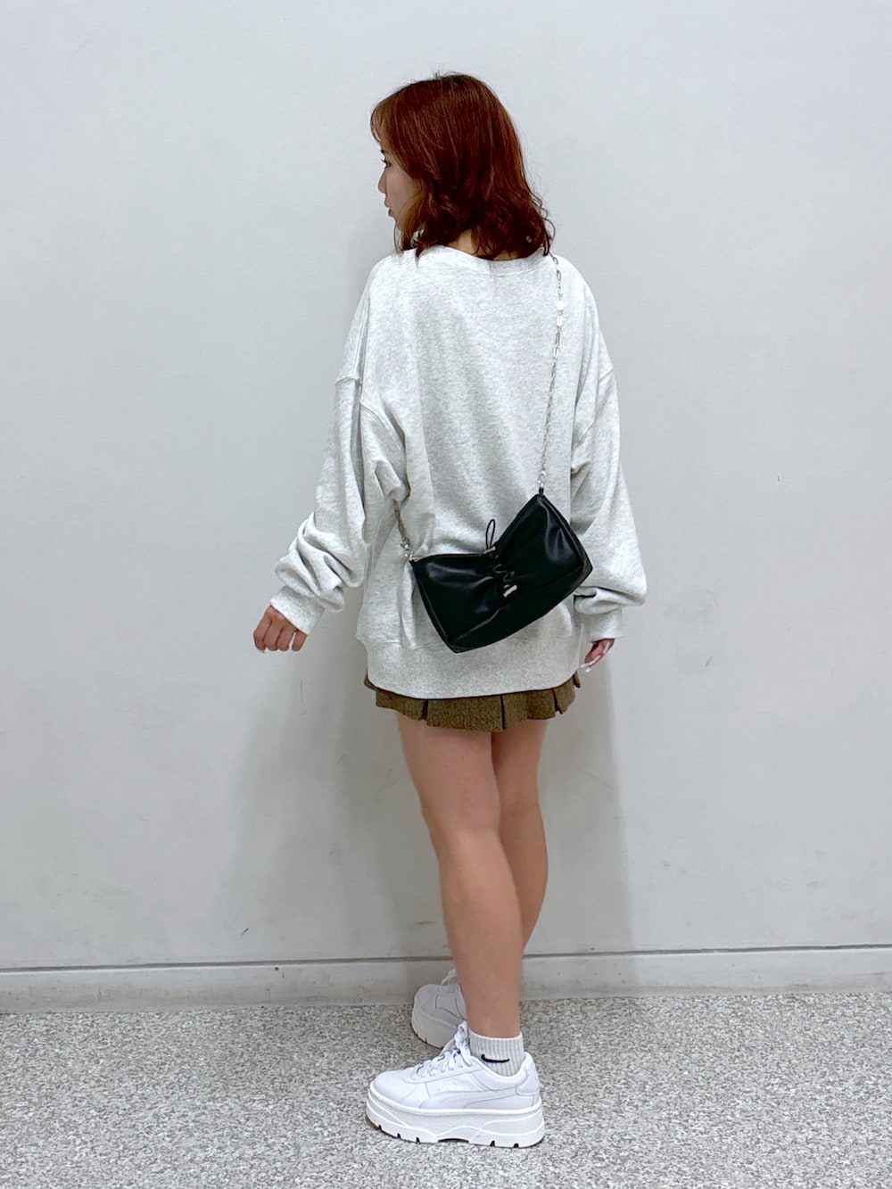 ホワイト系のスウェット、ブラウン系のスカート、ブラック系のハンドバッグを着用したレディースの秋コーディネートの4枚目の写真