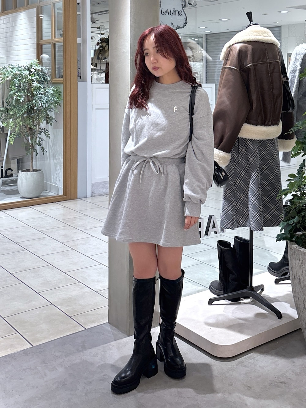 グレー系のワンピース、ブラック系のトートバッグ、ブラック系のブーツを着用したレディースの秋コーディネートの4枚目の写真