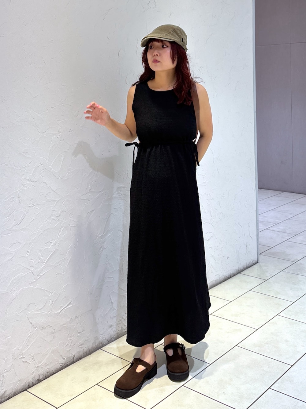 ブラック系のワンピース、ブラウン系のハンドバッグ、ホワイト系のキャミソールを着用したレディースの夏コーディネートの2枚目の写真