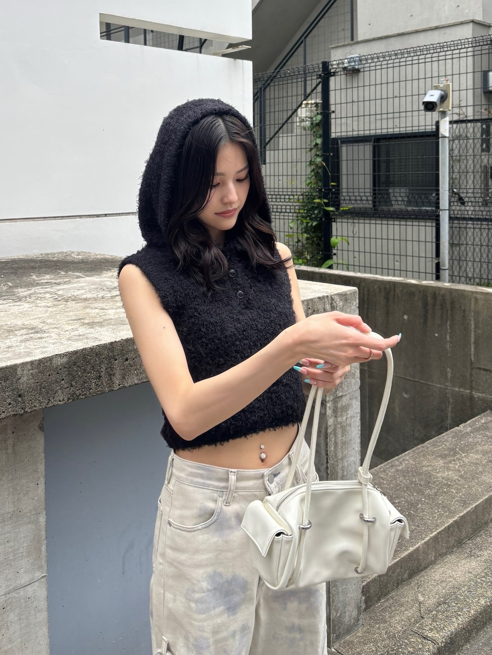 ブラック系のニット/セーター、ホワイト系のデニムパンツ、ホワイト系のハンドバッグを着用したレディースの春コーディネートの2枚目の写真