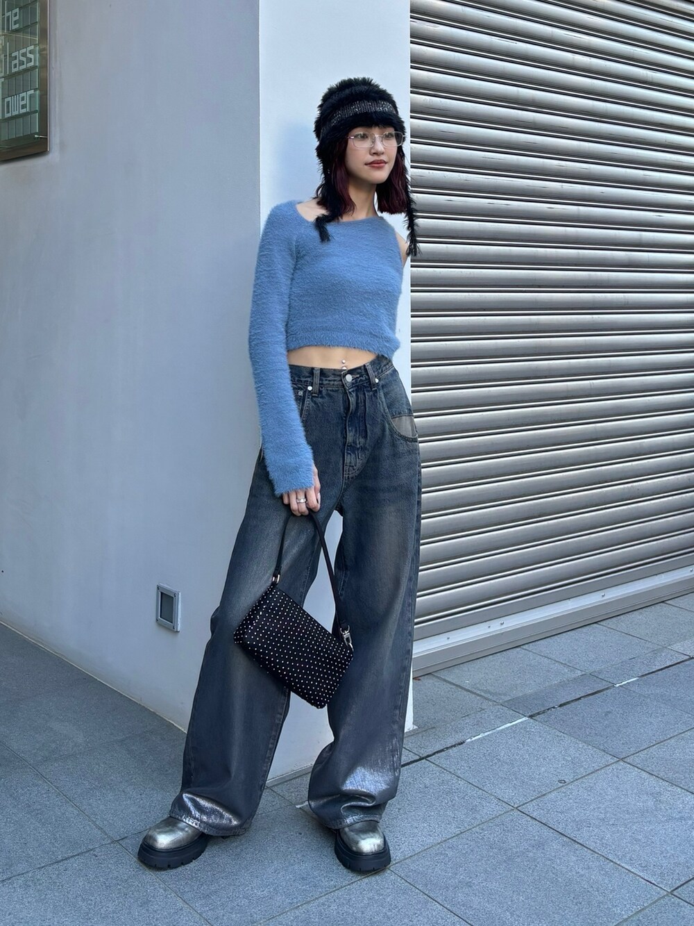 ブルー系のニット/セーター、ブルー系のデニムパンツ、ブラック系のハンドバッグを着用したレディースの秋コーディネートの2枚目の写真