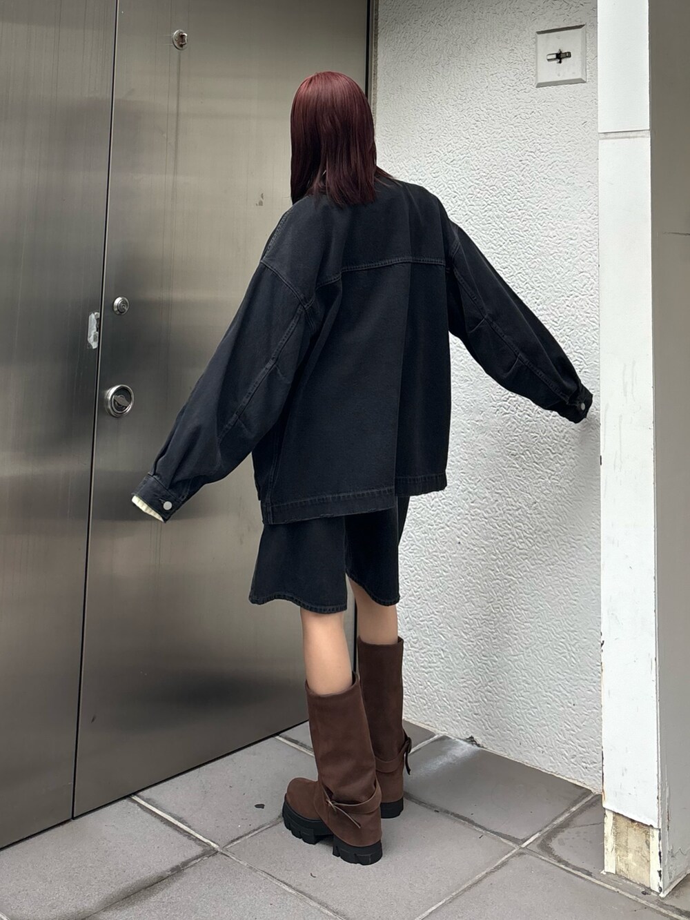 ブラック系のデニムパンツ、ブラウン系のブーツ、ブラック系のブルゾンを着用したレディースの冬コーディネートの2枚目の写真