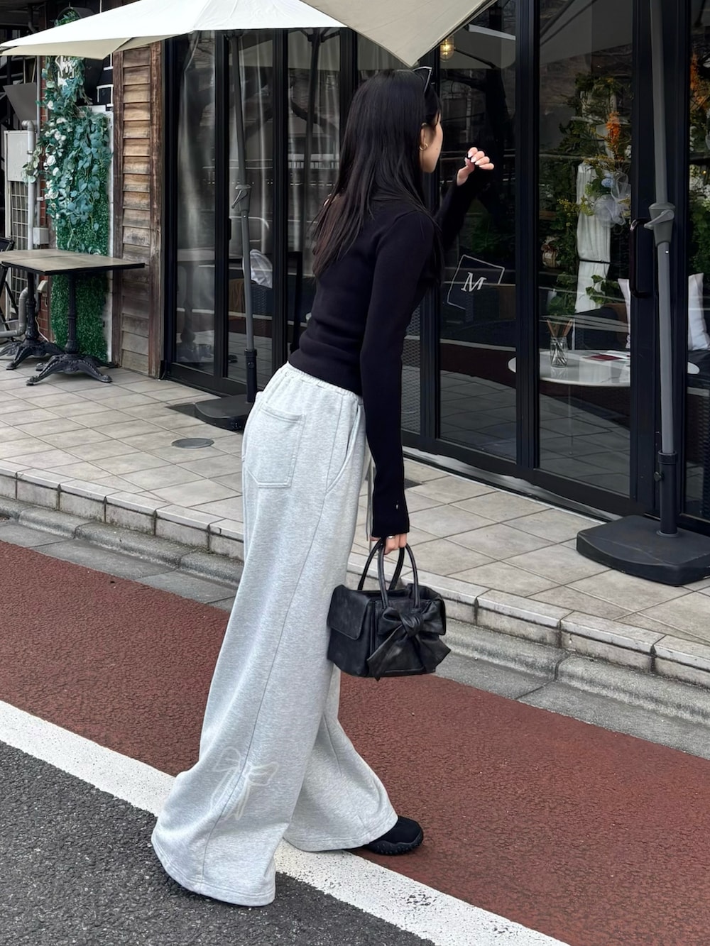 グレー系のスウェットパンツ、ブラック系のハンドバッグ、ブラック系のニット/セーターを着用したレディースの春コーディネートの3枚目の写真