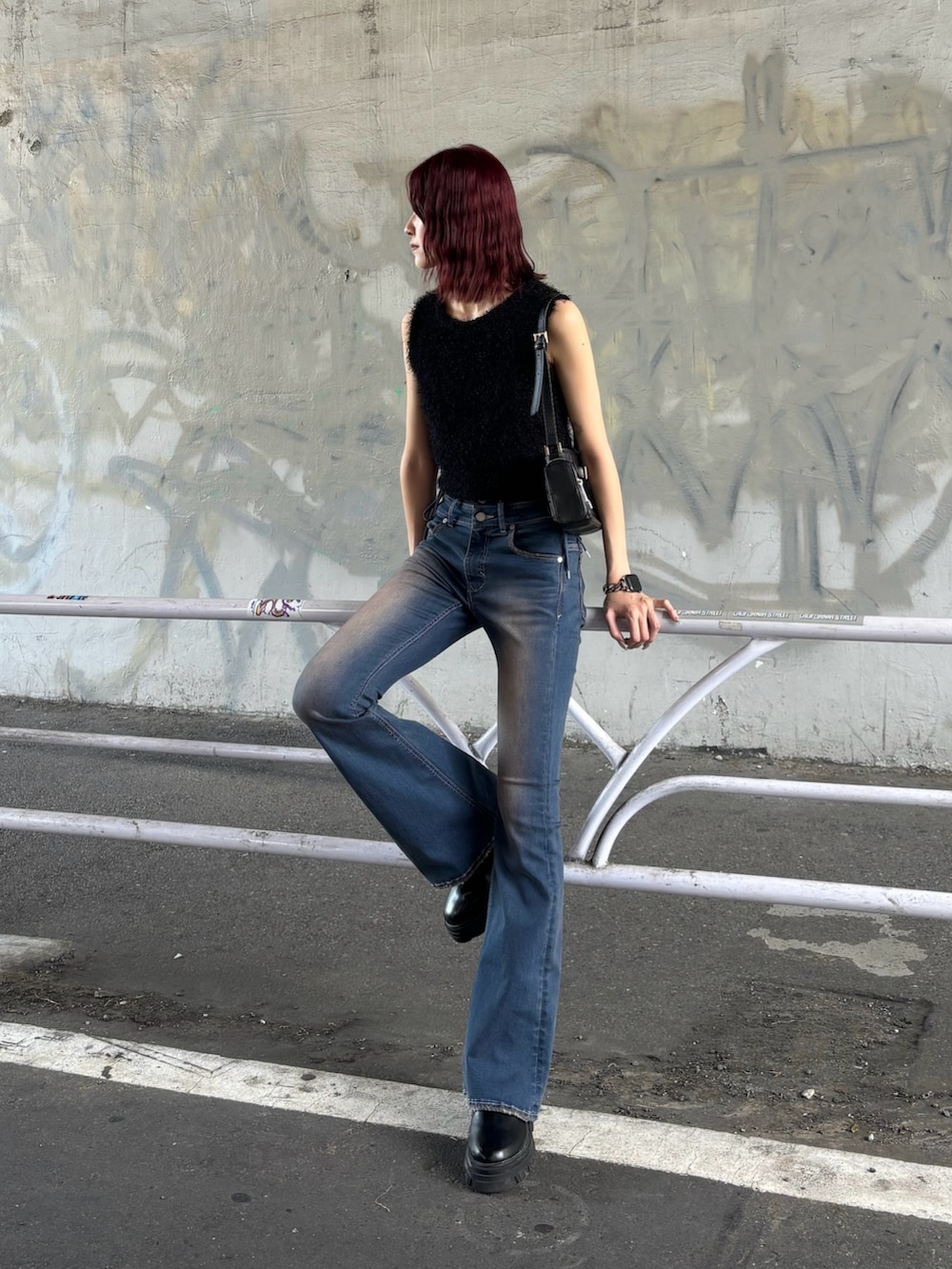 ブルー系のデニムパンツ、ブラック系のブーツ、ブラック系のショルダーバッグを着用したレディースの夏コーディネートの2枚目の写真