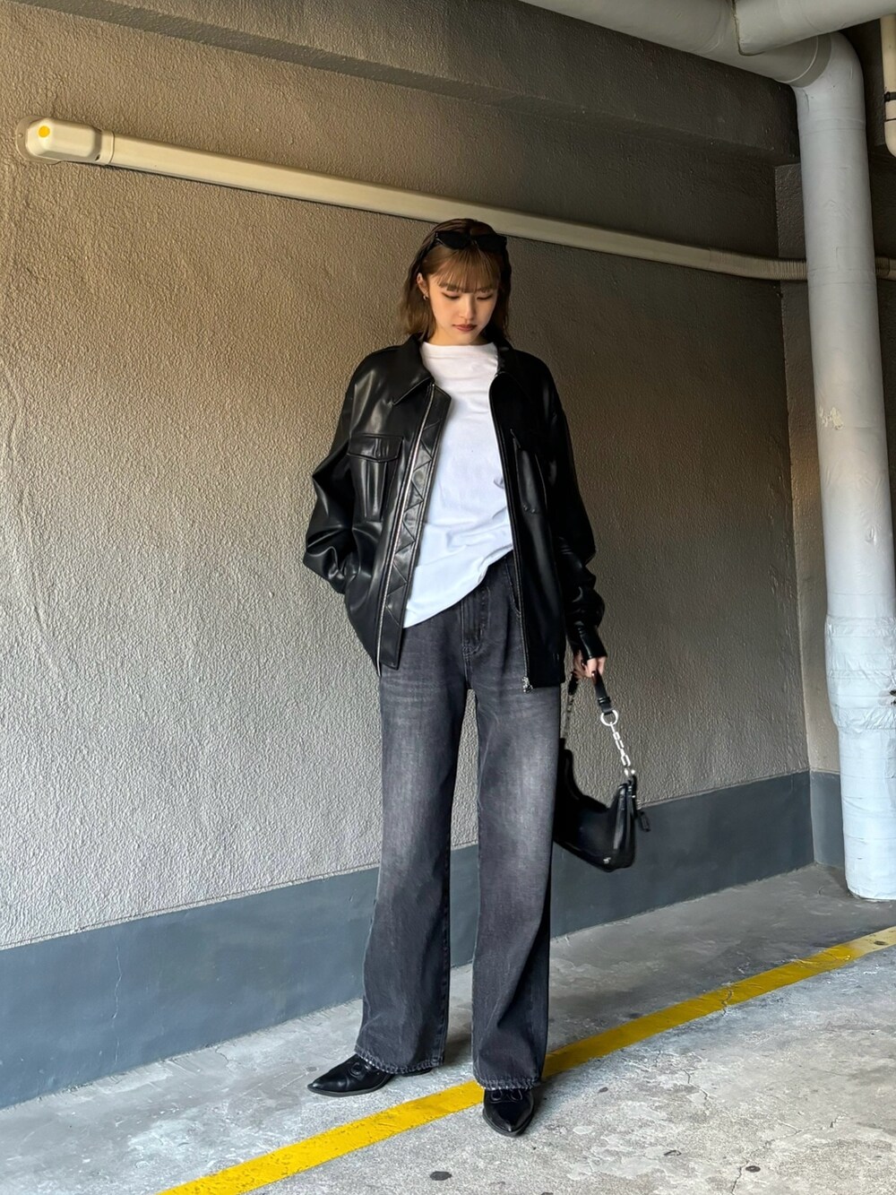 ブラック系のブルゾン、ホワイト系のTシャツ/カットソー、ブラック系のデニムパンツを着用したレディースの冬コーディネートの2枚目の写真