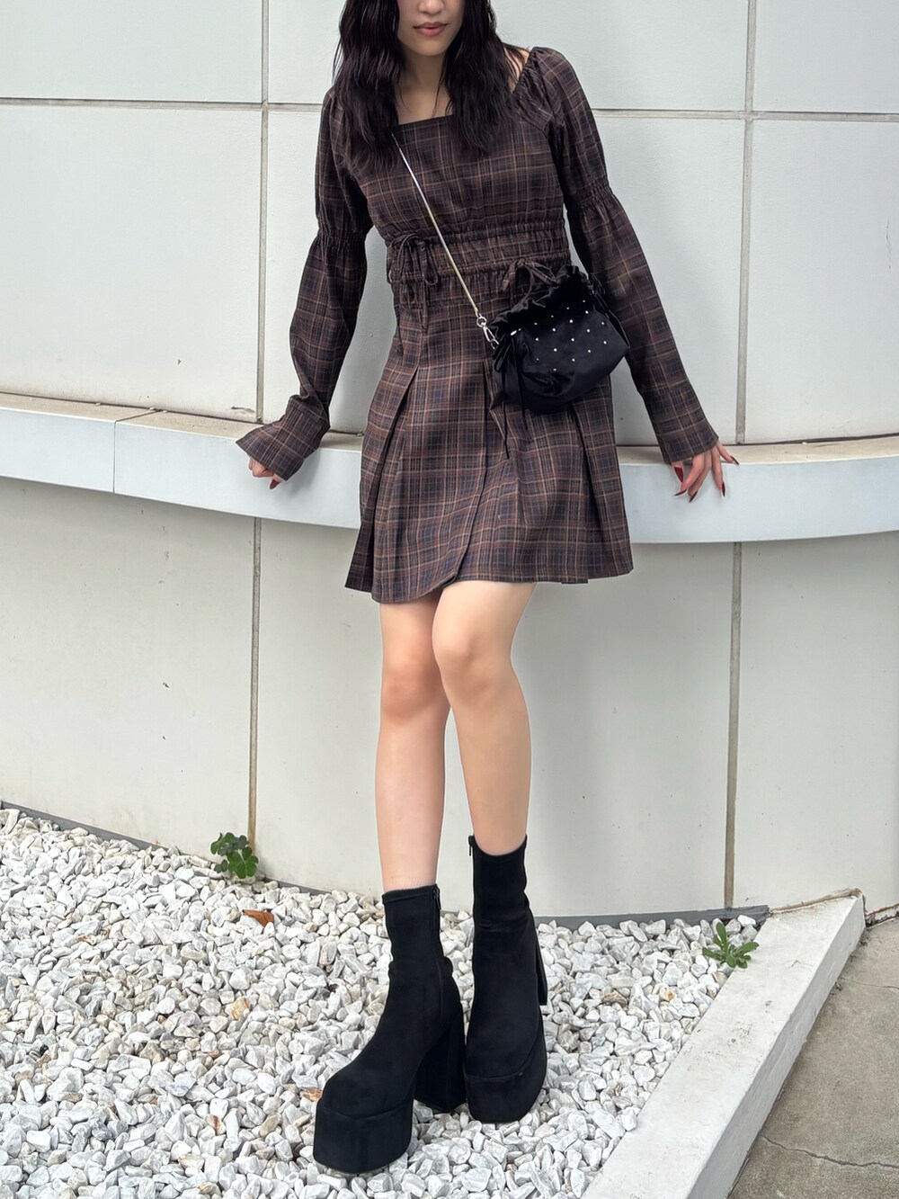 ブラック系のブーツ、ブラウン系のワンピース、ブラック系のハンドバッグを着用したレディースの秋コーディネートの2枚目の写真
