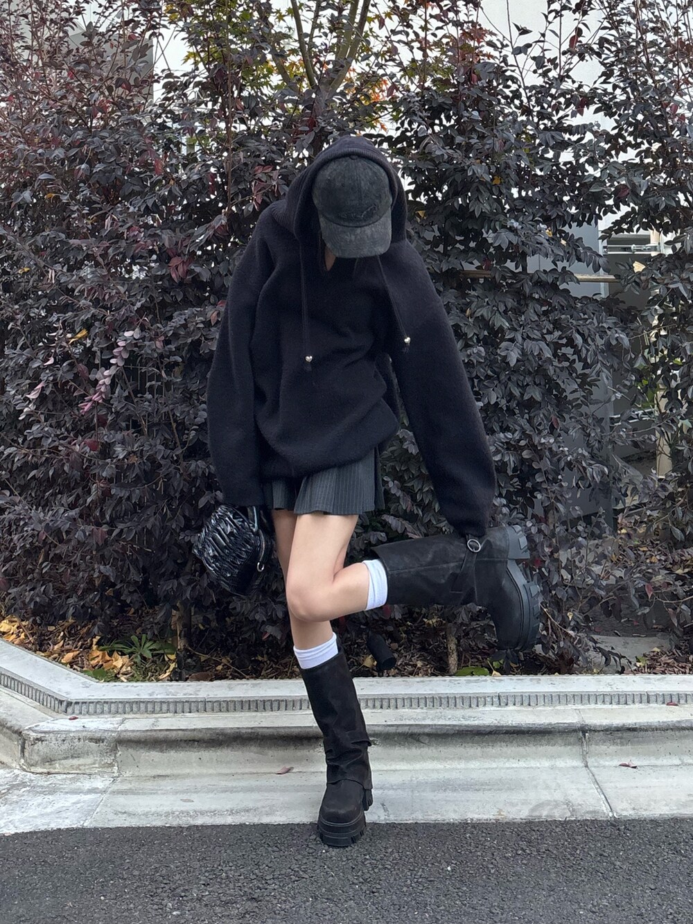 グレー系のスカート、ブラック系のブーツ、ブラック系のニット/セーターを着用したレディースの冬コーディネートの2枚目の写真