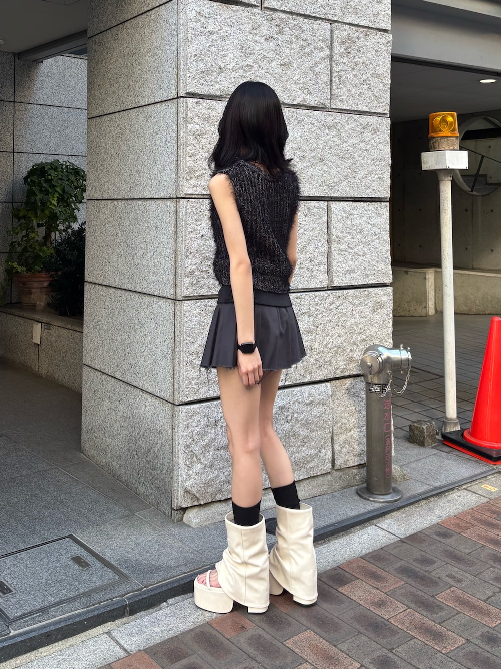 グレー系のスカート、ホワイト系のサンダル、ブラック系のニット/セーターを着用したレディースの冬コーディネートの2枚目の写真