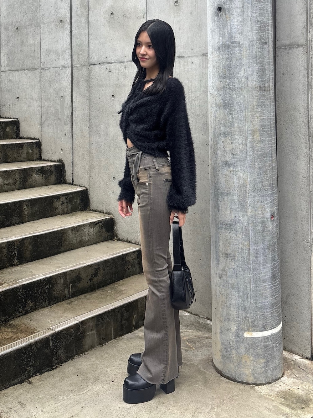 グレー系のデニムパンツ、ブラック系のブーツ、ブラック系のニット/セーターを着用したレディースの秋コーディネートの2枚目の写真