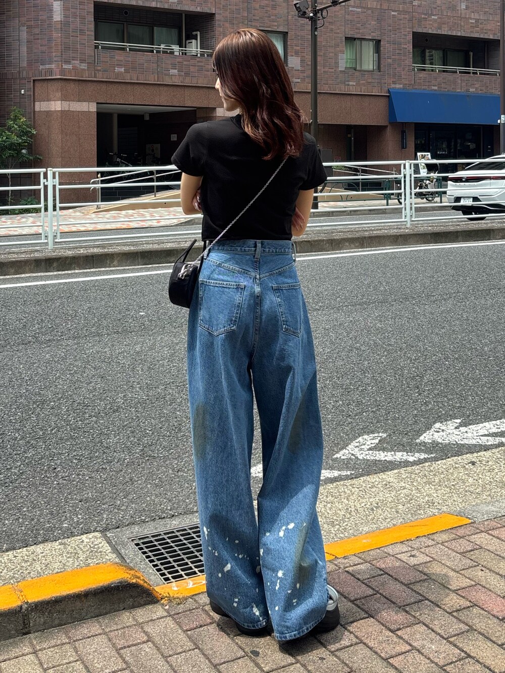 ブルー系のデニムパンツ、グレー系のサンダル、ブラック系のハンドバッグを着用したレディースの夏コーディネートの2枚目の写真