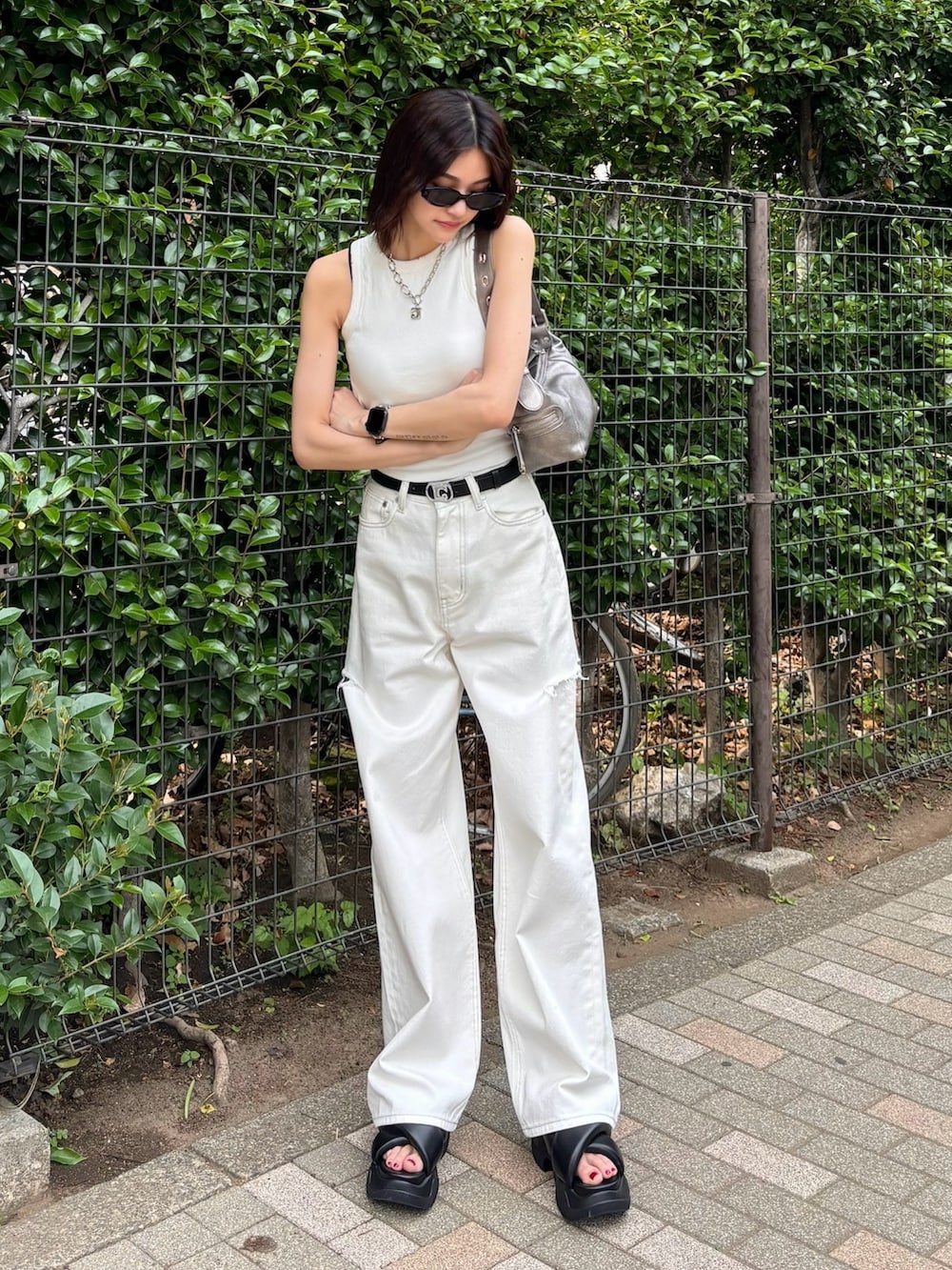 ホワイト系のデニムパンツ、ブラック系のサンダル、ホワイト系のタンクトップを着用したレディースの夏コーディネートの2枚目の写真