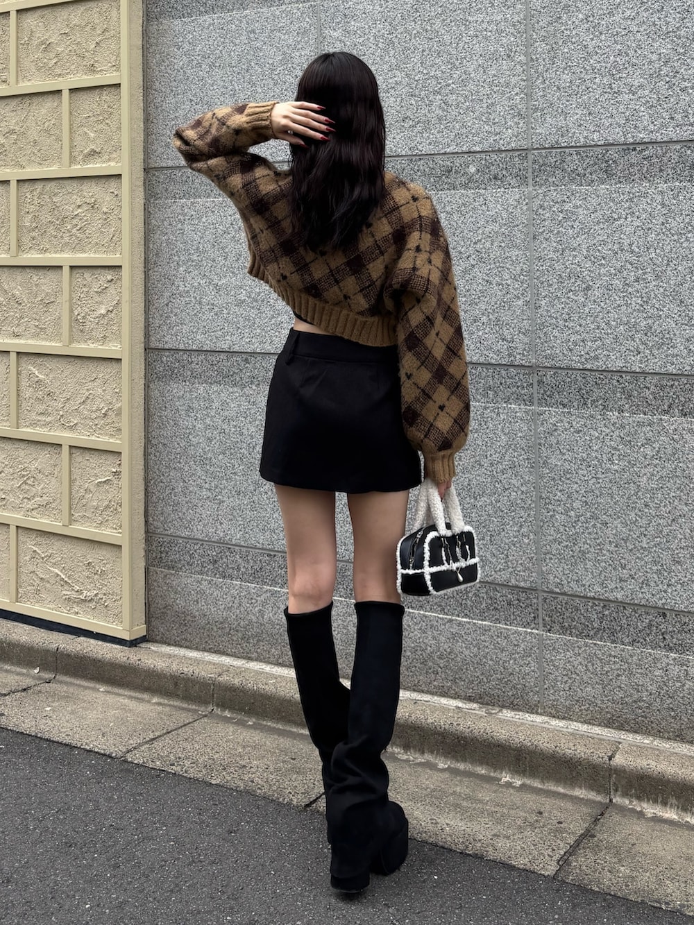 ブラック系のブーツ、ベージュ系のニット/セーター、ブラック系のスカートを着用したレディースの秋コーディネートの2枚目の写真