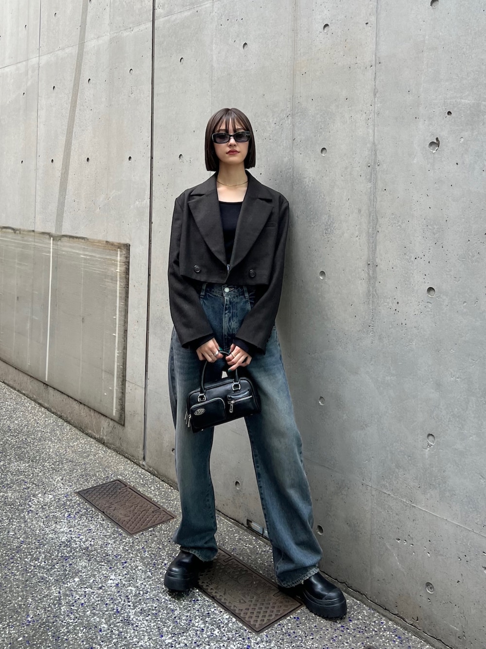 ブルー系のデニムパンツ、ブラック系のブーツ、ブラック系のハンドバッグを着用したレディースの夏コーディネートの2枚目の写真
