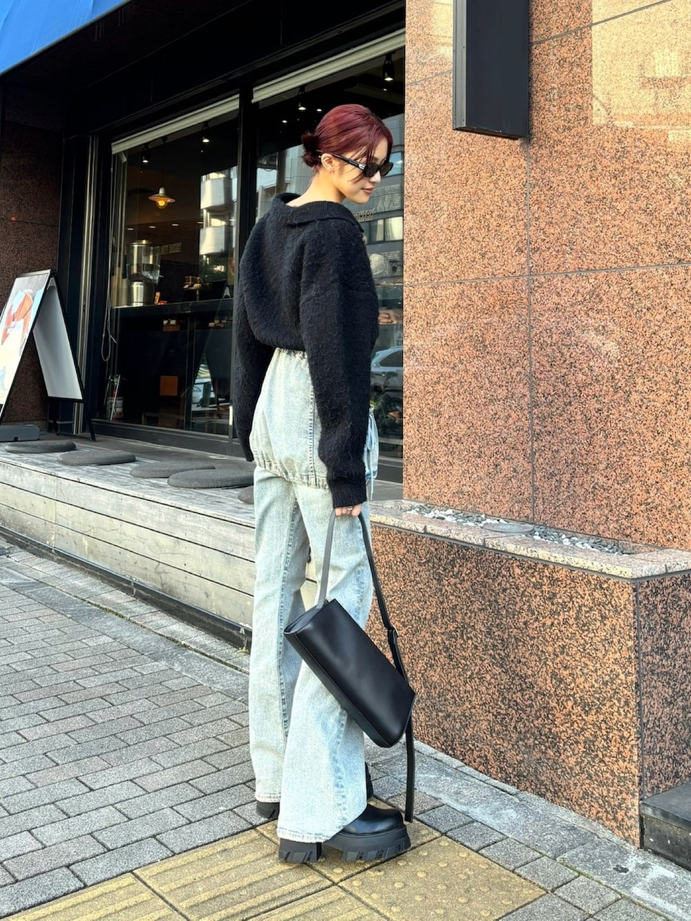 ブルー系のデニムパンツ、ブラック系のブーツ、ブラック系のニット/セーターを着用したレディースの秋コーディネートの2枚目の写真