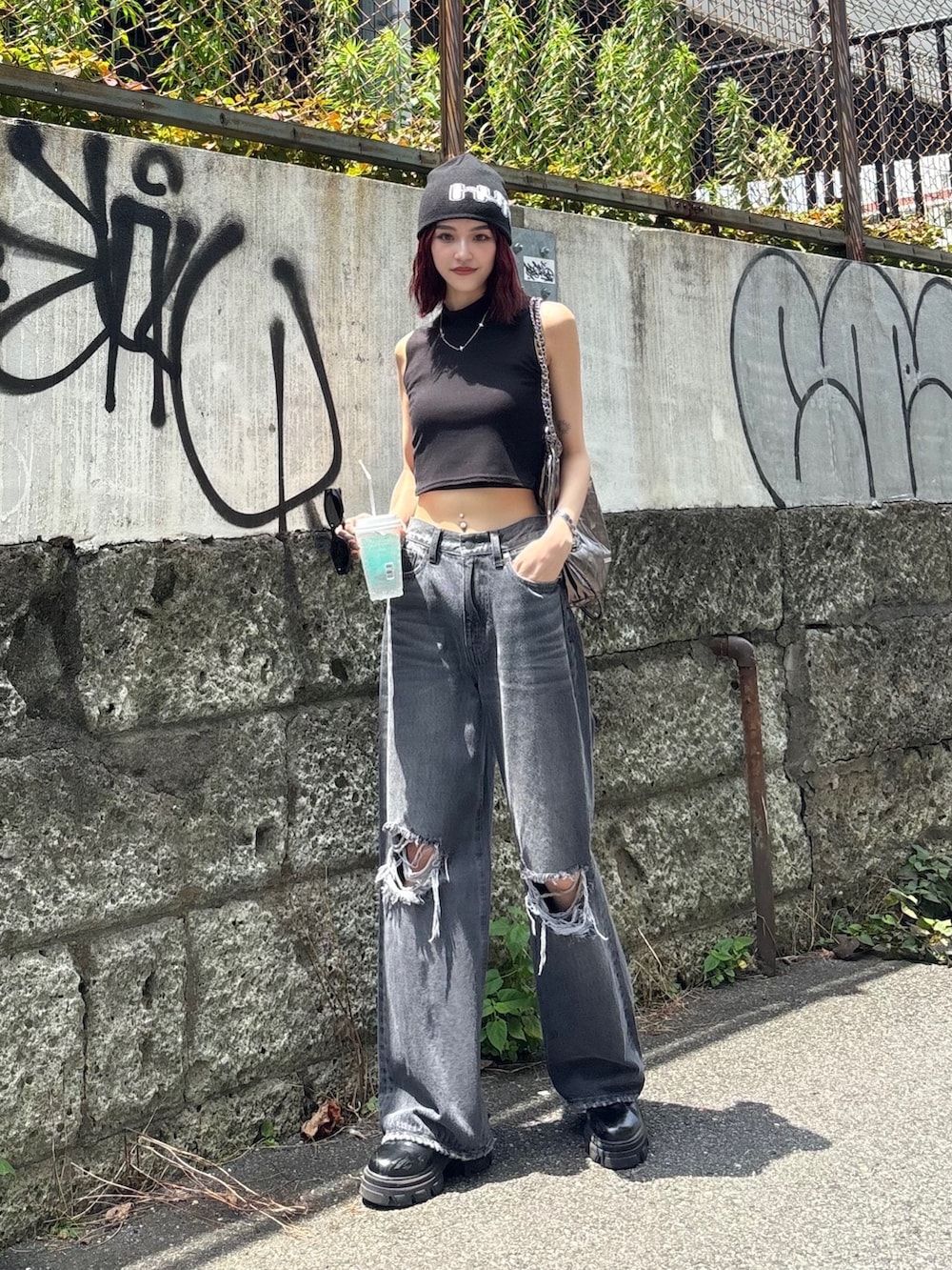 グレー系のデニムパンツ、ブラック系のブーツ、ブラック系のタンクトップを着用したレディースの夏コーディネートの2枚目の写真