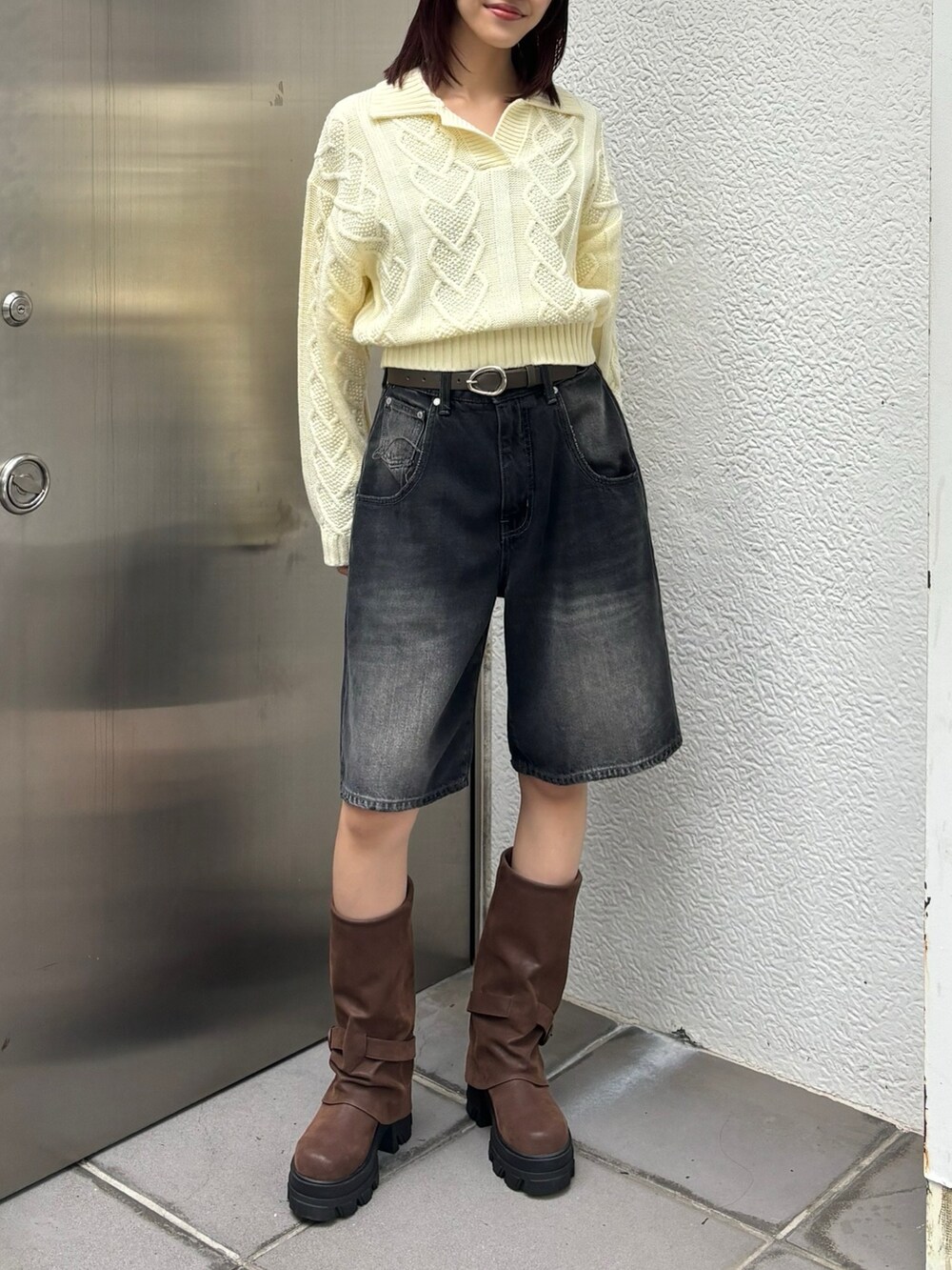 ブラック系のデニムパンツ、ブラウン系のブーツ、ホワイト系のニット/セーターを着用したレディースの秋コーディネートの2枚目の写真