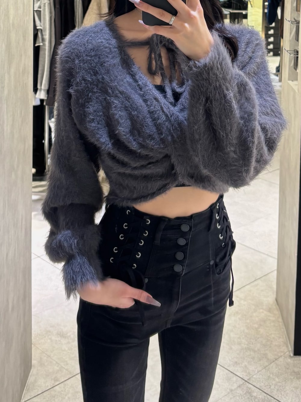 ブラック系のデニムパンツ、ブラック系のブーツ、グレー系のニット/セーターを着用したレディースの秋コーディネートの2枚目の写真