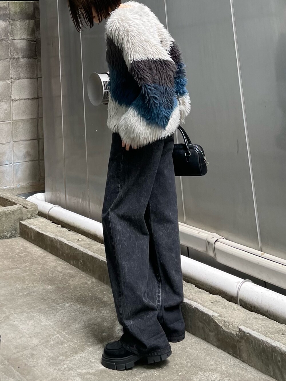 ブラック系のデニムパンツ、ブラック系のローファー、ブラック系のハンドバッグを着用したレディースの秋コーディネートの2枚目の写真