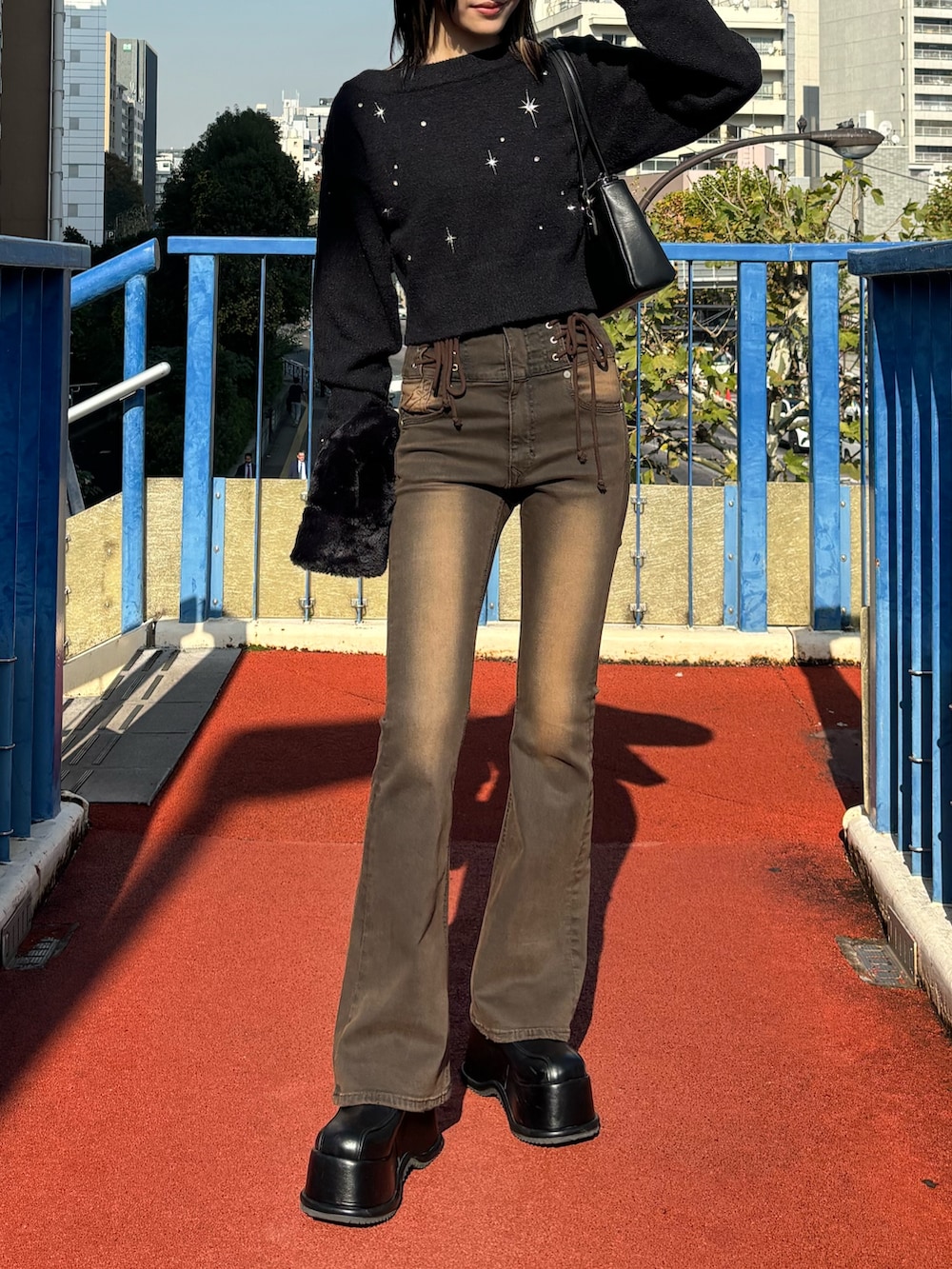 ブラウン系のデニムパンツ、ブラック系のローファー、ブラック系のニット/セーターを着用したレディースの冬コーディネートの2枚目の写真