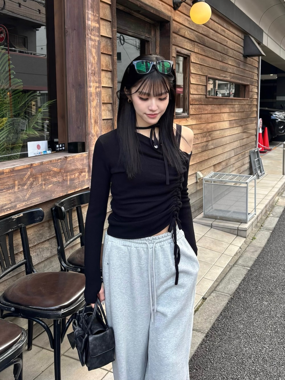 グレー系のスウェットパンツ、ブラック系のハンドバッグ、ブラック系のニット/セーターを着用したレディースの春コーディネートの2枚目の写真