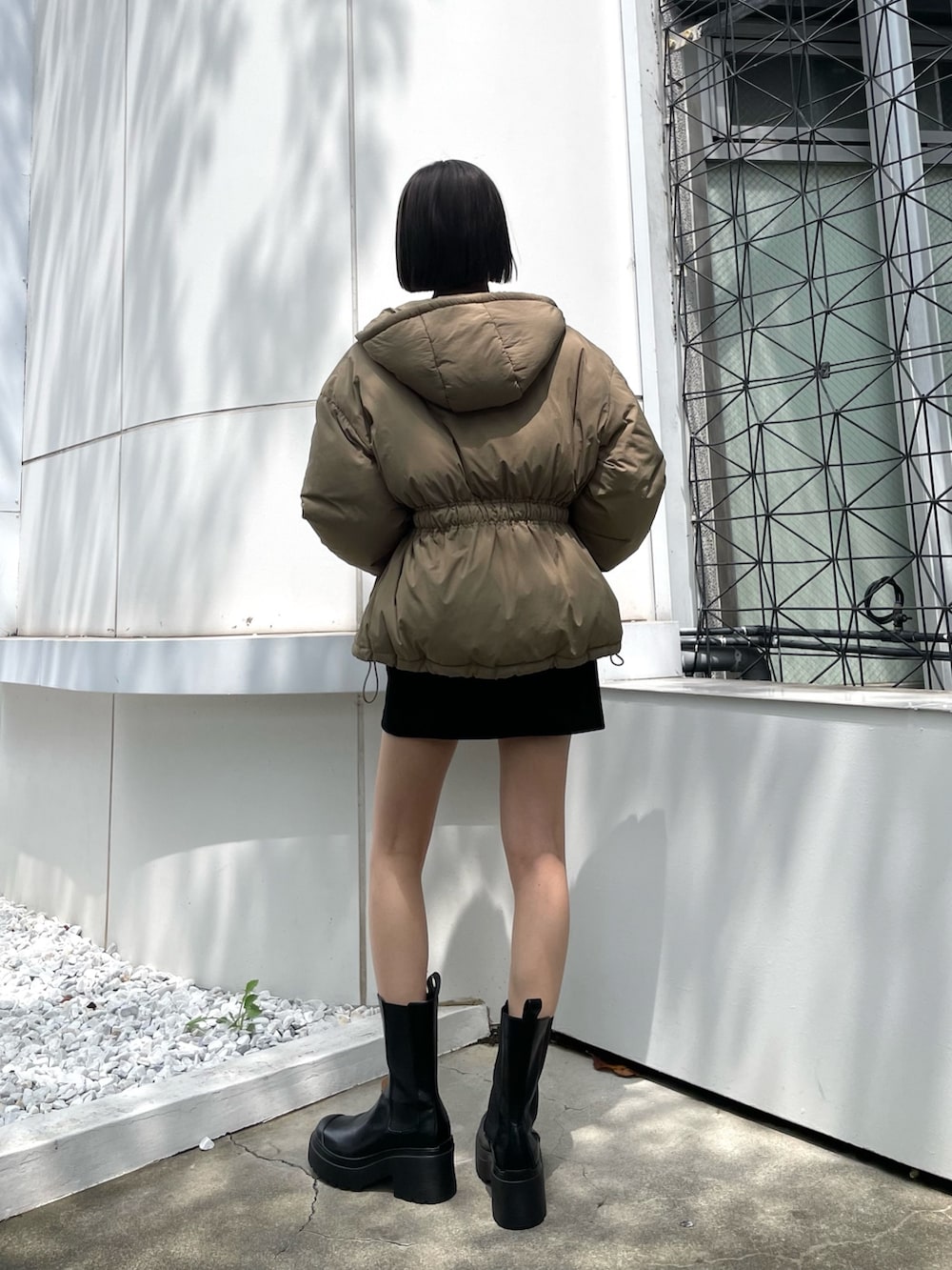 ブラック系のスカート、ブラック系のブーツ、グリーン系のブルゾンを着用したレディースの冬コーディネートの2枚目の写真