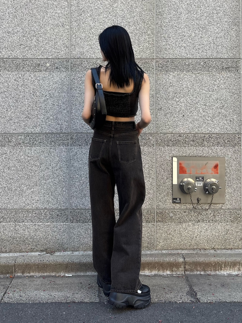 ブラック系のタンクトップ、ブラック系のデニムパンツ、ブラック系のハンドバッグを着用したレディースの春コーディネートの2枚目の写真