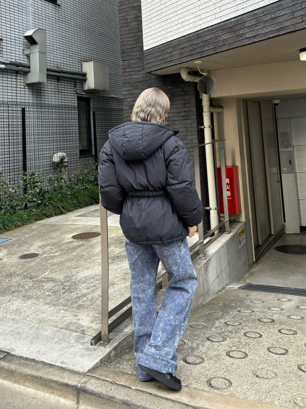 パープル系のデニムパンツ、ブラック系のニット/セーター、ブラック系のブルゾンを着用したレディースの秋コーディネートの2枚目の写真